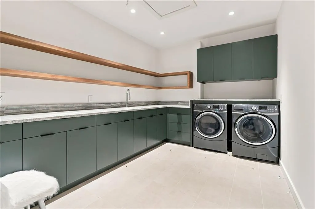 Laundry room featuring extensive green cabinetry, a stone-finish countertop, wood-finish shelving, and recessed lighting