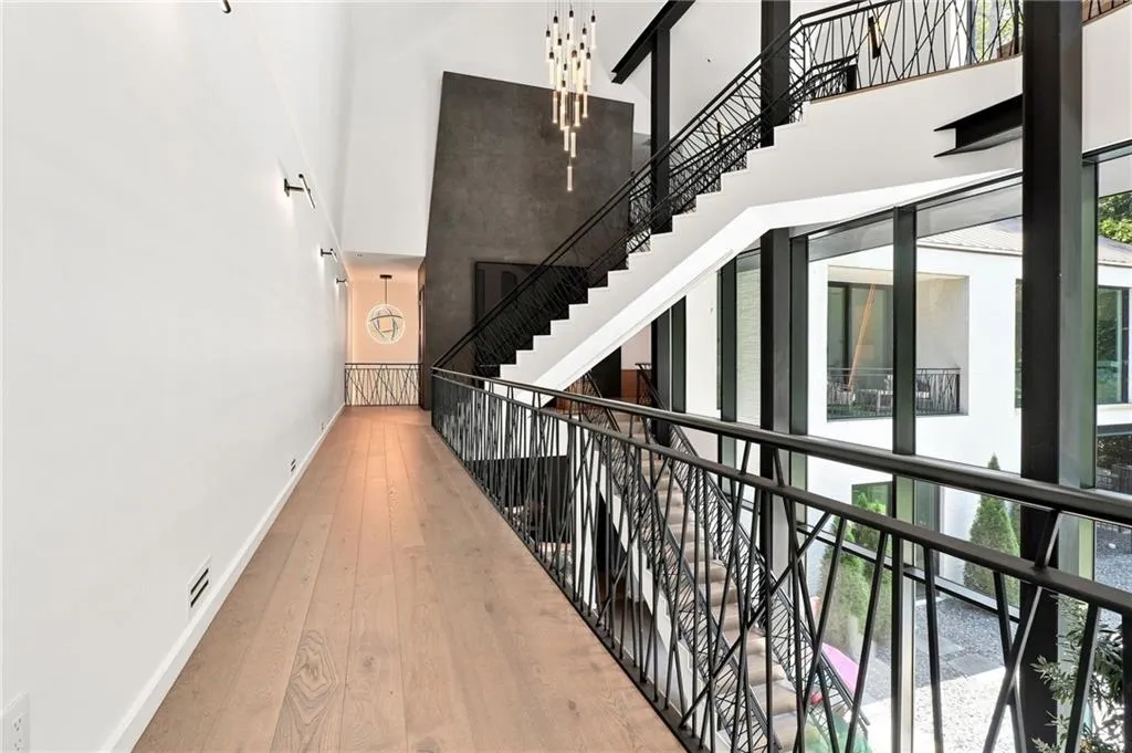Hardwood flooring extending through a brightly lit hallway, accentuated by modern wall sconces