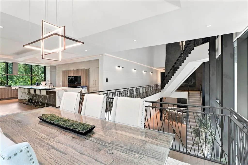 Open-concept living space with a multi-level staircase, kitchen island with integrated seating, and large-format windows