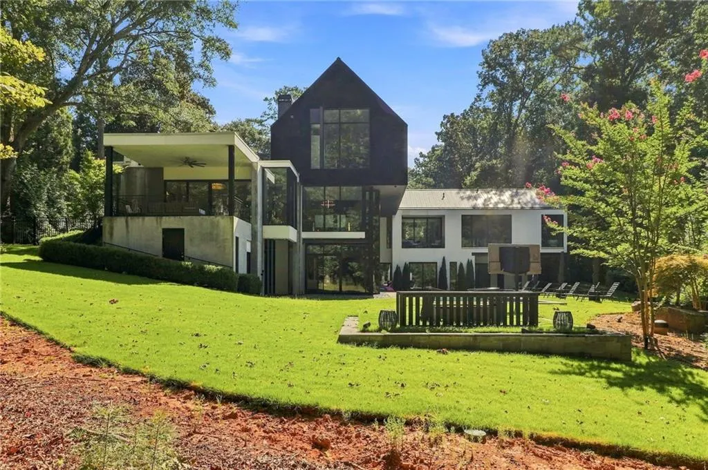 Modern architecture featuring a gabled roofline, expansive windows, and a covered balcony with a ceiling fan