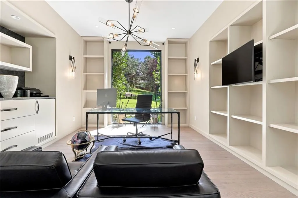 Built-in shelving, wood-finish flooring, recessed lighting, modern chandelier, and a large picture window