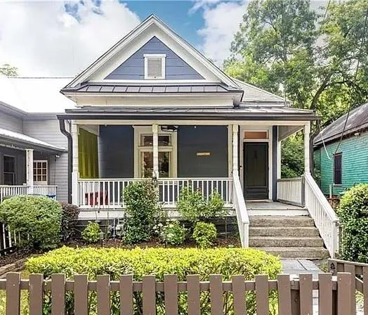 Exterior featuring a covered front porch, white railing, blue siding, and a gabled roofline