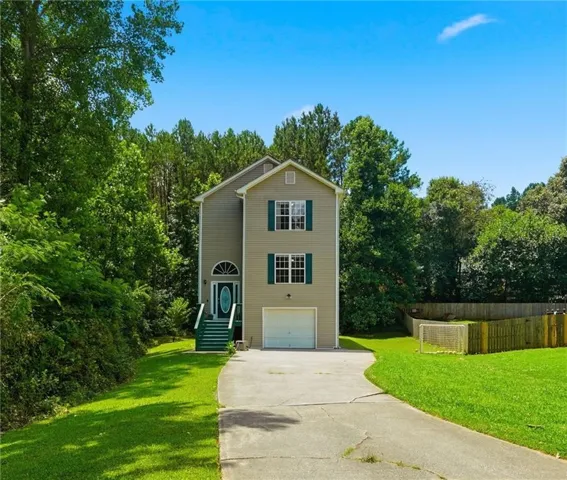 Two-story residence featuring light tan siding and a recessed front entrance with an arched transom window