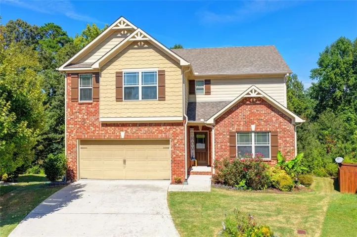 Brick and siding exterior with decorative gables, an attached garage, and a concrete driveway