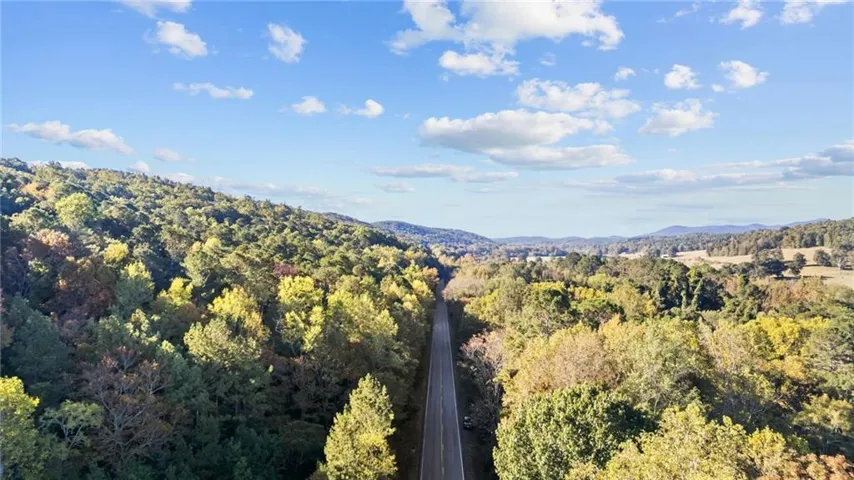 Expansive surrounding natural landscape with mature trees and distant hills
