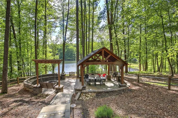 This beautiful outdoor entertaining area features a covered dining area along with a propane firepit surrounded by a stacked stone seating bench. Perfect place to enjoy the fabulous lake views and spend time with family and friends.