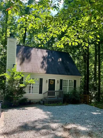 Siding exterior featuring a dark asphalt shingle roof, chimney, and a gravel driveway