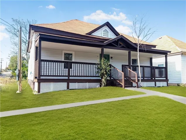 White siding exterior with a welcoming covered front porch, dark trim accents, and a light-colored roof