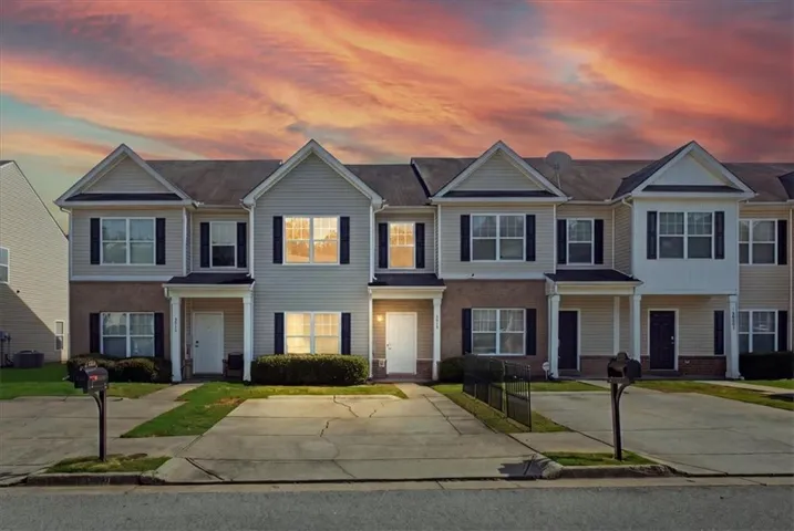 Two-story townhome with siding exterior and brick accents, featuring a covered entry and attached asphalt driveway
