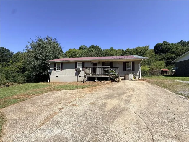 Charming single-story residence featuring a covered front porch with railing, durable concrete driveway, and metal roof