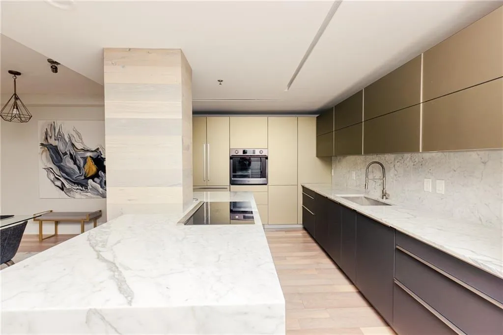 Kitchen featuring stainless steel oven, light wood-type flooring, light stone countertops, and tasteful backsplash