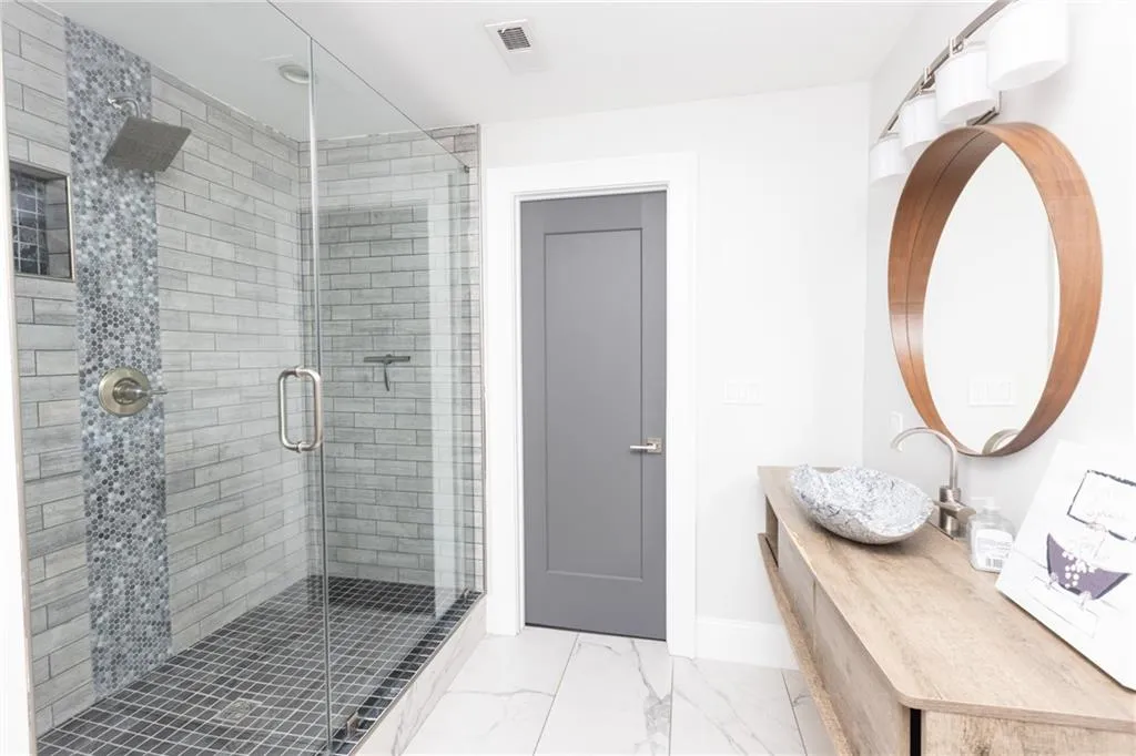 Full bathroom featuring marble finish flooring, a shower stall, and vanity
