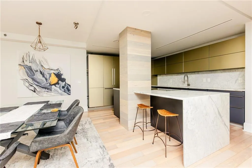 Kitchen featuring modern cabinets, tasteful backsplash, a breakfast bar area, light wood-type flooring, and light stone counters