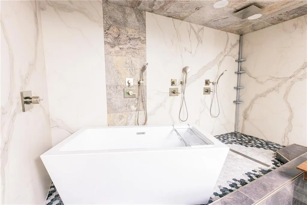 Full bath featuring a marble finish shower and a freestanding tub