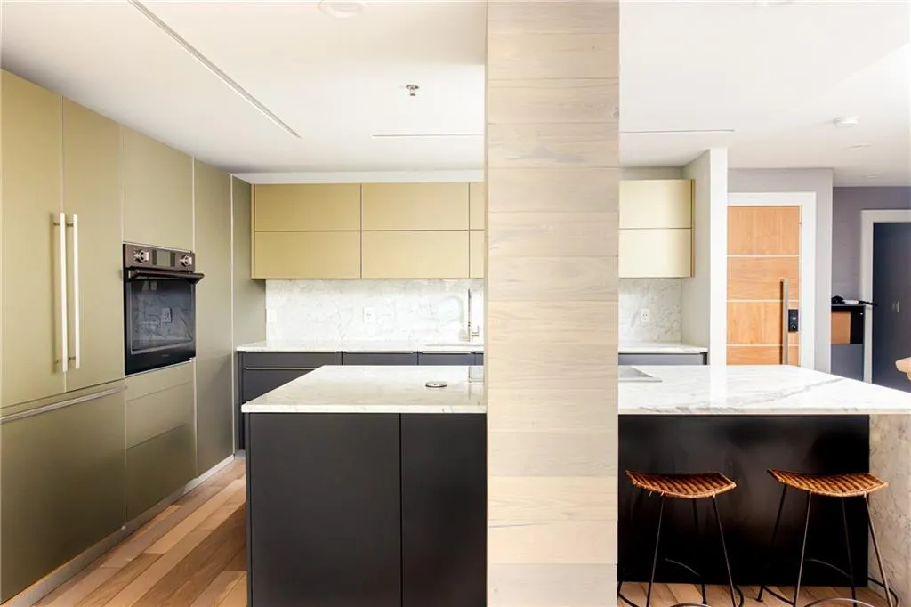 Kitchen with black oven, a kitchen island, modern cabinets, and cream cabinets