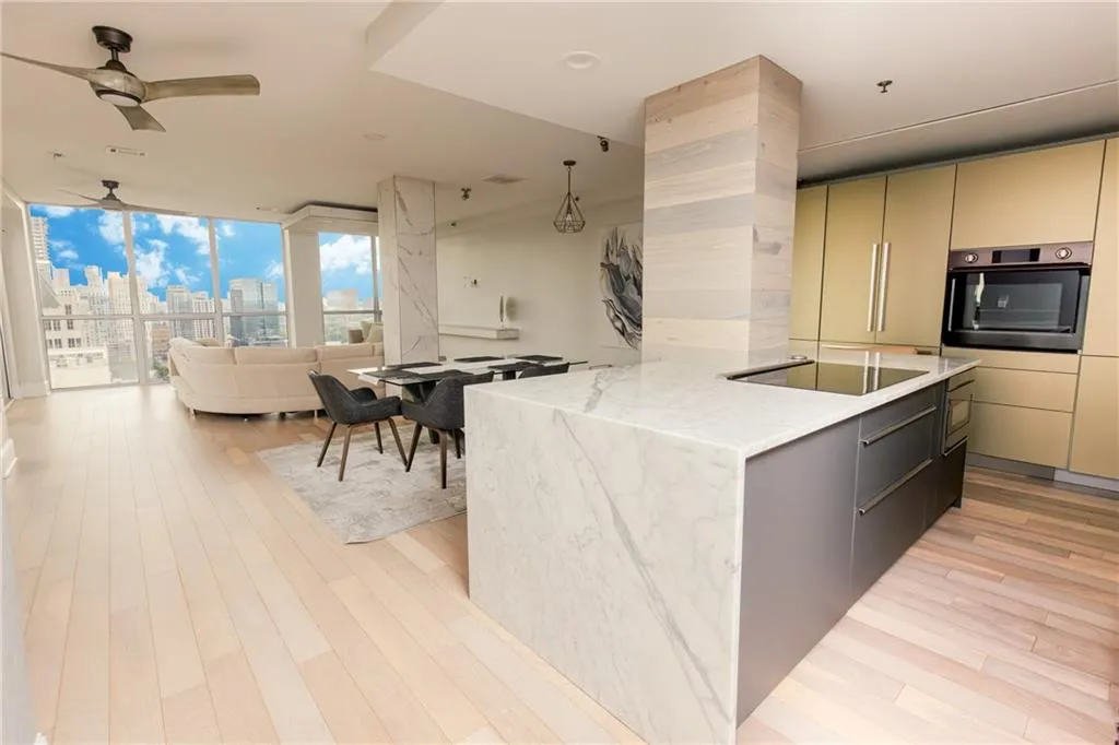 Kitchen with oven, a skyline view, a ceiling fan, light wood-style floors, and a wall of windows