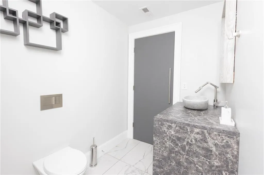 Half bathroom with marble finish floors and vanity