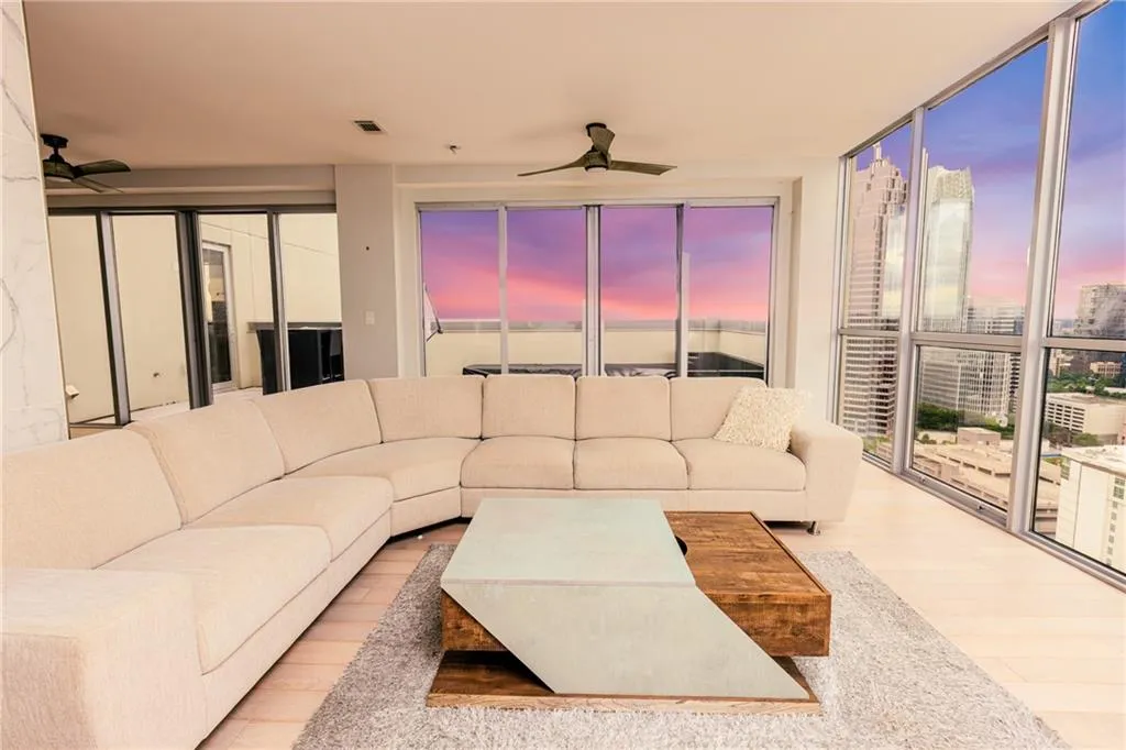 Living area with ceiling fan, a wall of windows, wood finished floors, and a view of city