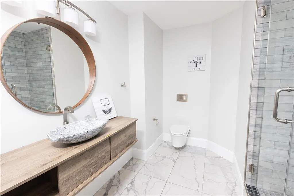 Bathroom featuring vanity, marble finish flooring, and a shower stall
