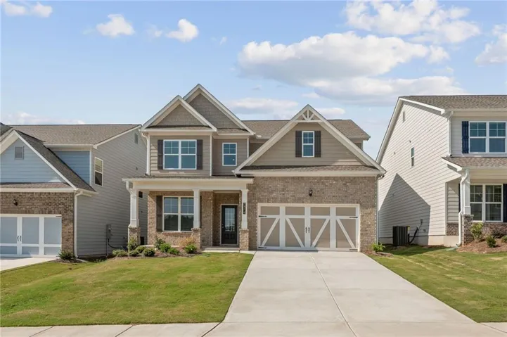 Brick and siding exterior with multiple gables, a covered front entry, a two-car garage, a concrete driveway, and a manicured front lawn