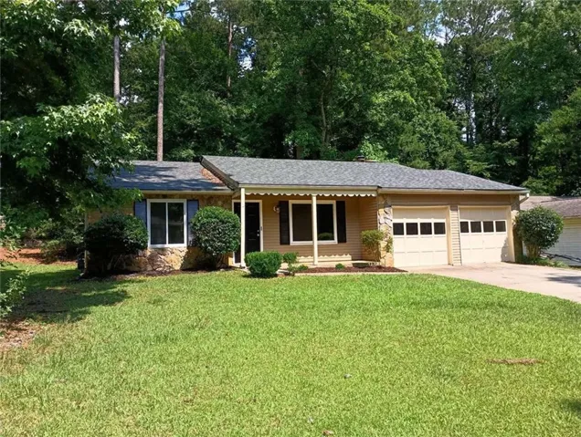 Ranch-style residence featuring a stone and siding exterior, a gray asphalt shingle roof, and a two-car garage with panel doors