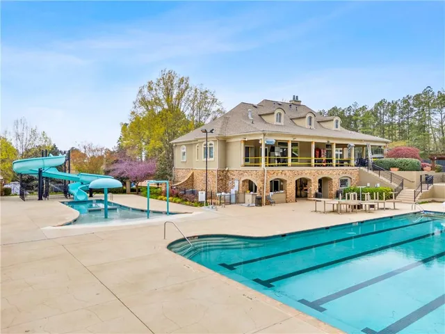 Community pool featuring a patio area, a water play area, a water slide, and a balcony
