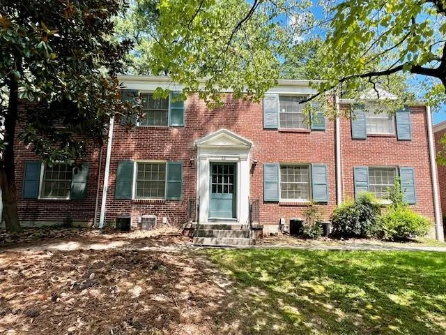 Brick exterior with decorative shutters, a central entrance, and a symmetrical facade