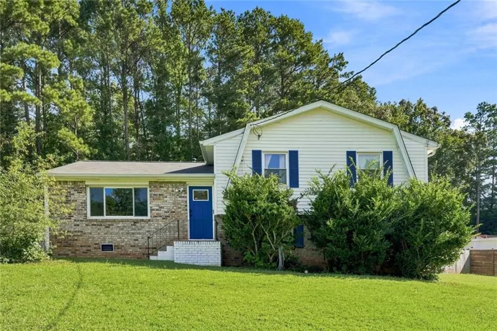 Traditional split-level residence featuring a brick facade, white siding, and a vibrant blue entry door
