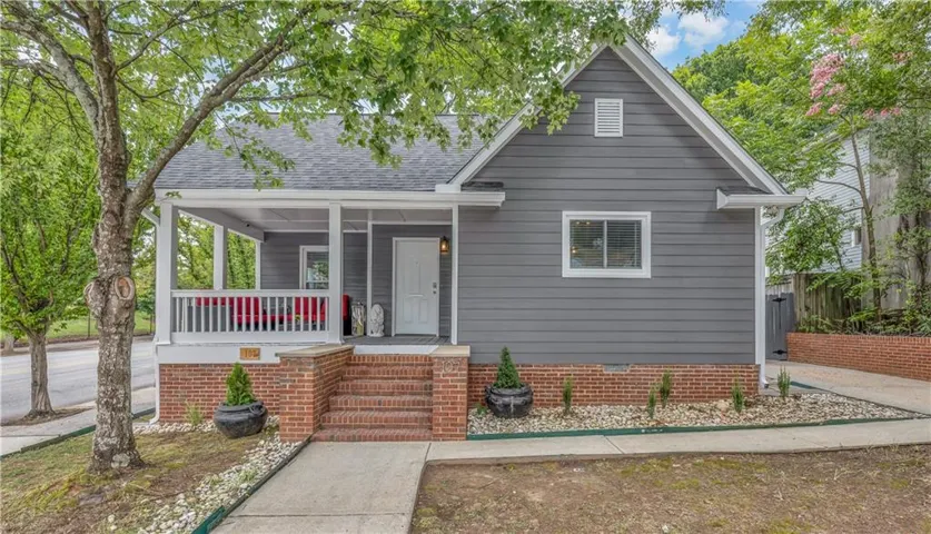 Siding exterior with a covered front porch, brick foundation, and a concrete pathway