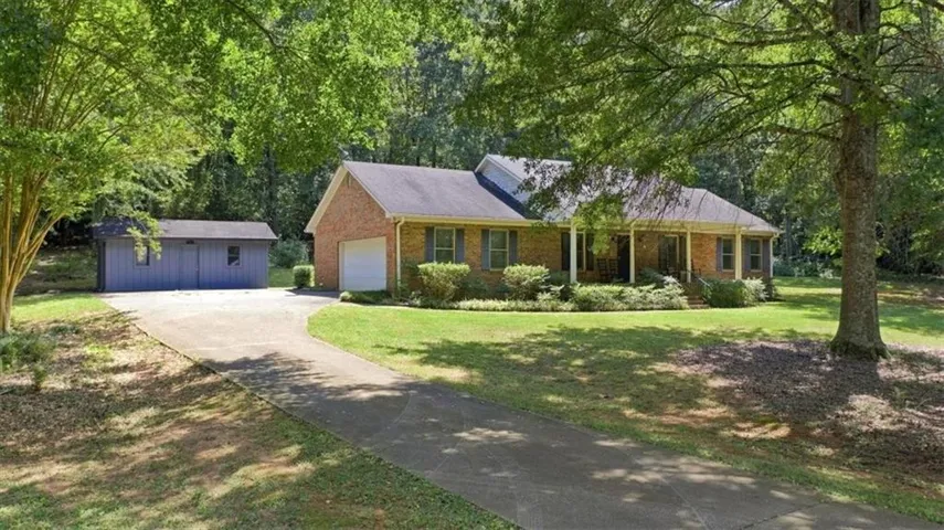 Brick exterior with a covered front porch, attached garage, and a separate outbuilding