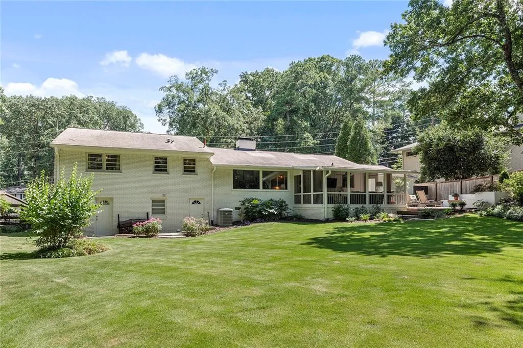Rear view of property with brick siding, a sunroom, a garage, and a chimney