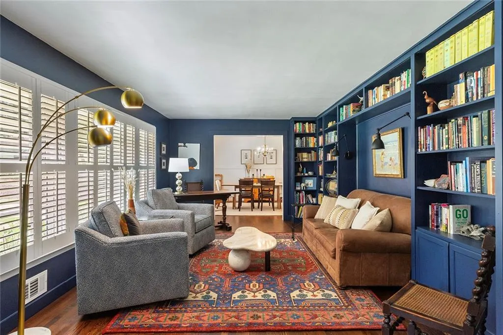 Living room with a chandelier, wood finished floors, and built in shelves
