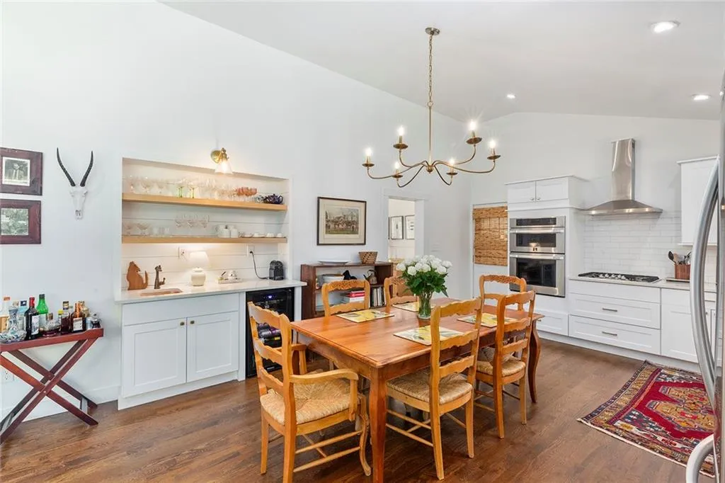 Dining room featuring lofted ceiling, dark wood-type flooring, wine cooler, a chandelier, and recessed lighting