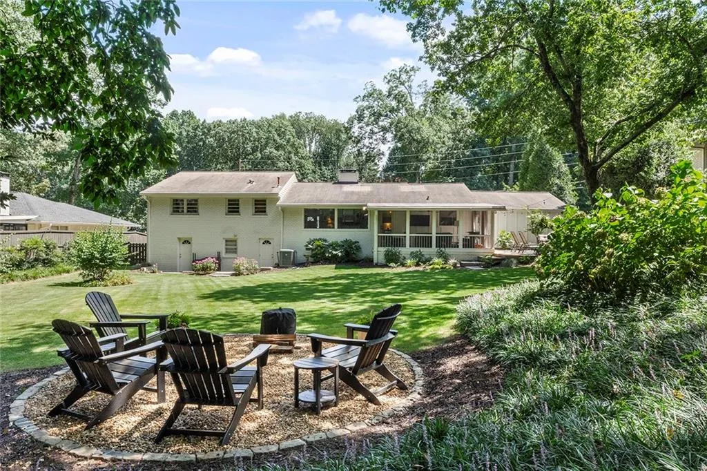 Back of house with a fire pit, a lawn, and a chimney
