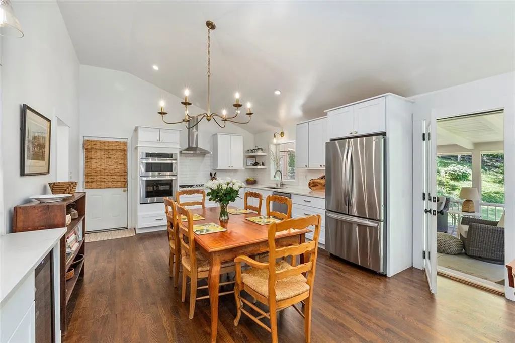 Dining area featuring vaulted ceiling, dark wood-style flooring, a chandelier, and recessed lighting