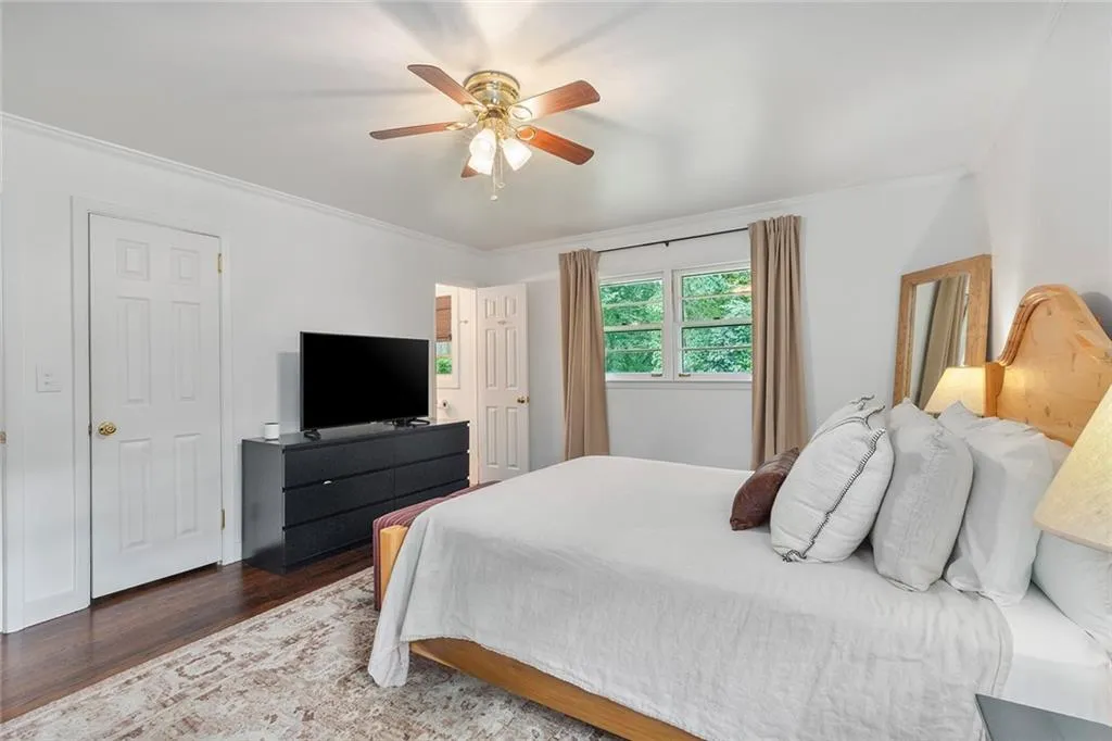 Bedroom with ornamental molding, wood finished floors, and ceiling fan