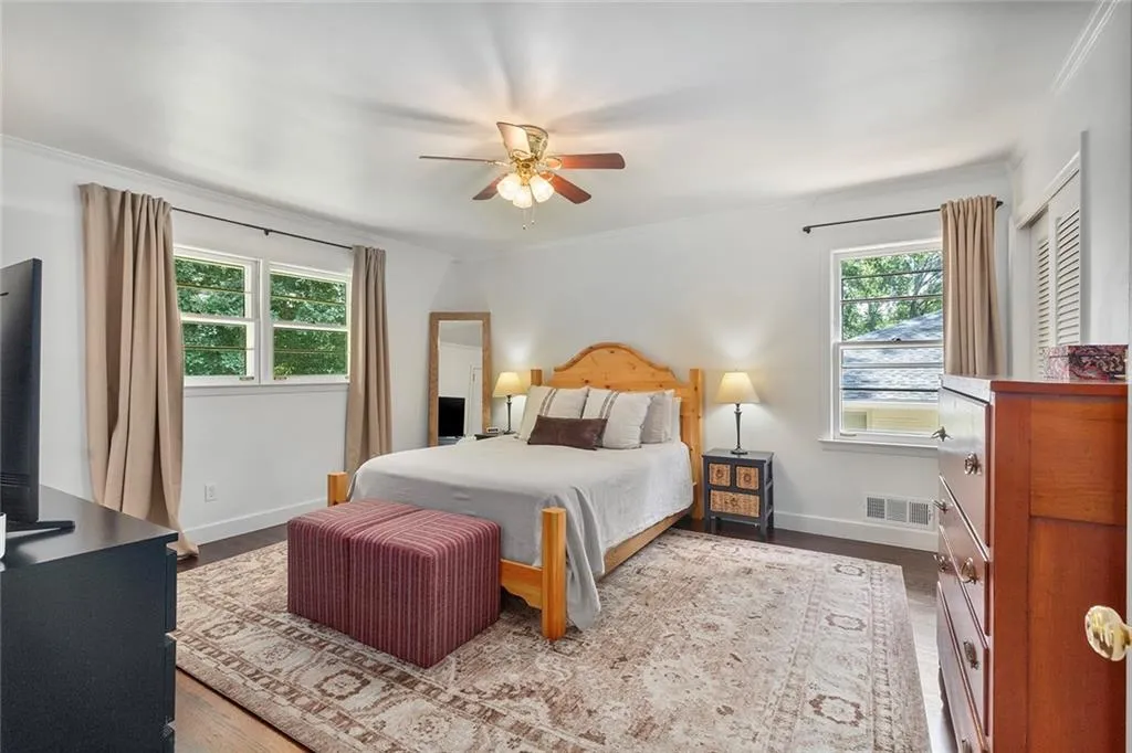 Bedroom featuring multiple windows, ornamental molding, wood finished floors, and a ceiling fan