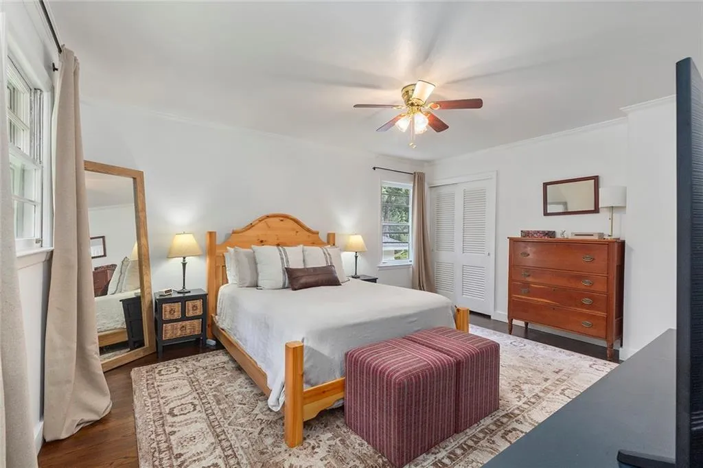 Bedroom with ornamental molding, a closet, wood finished floors, and ceiling fan