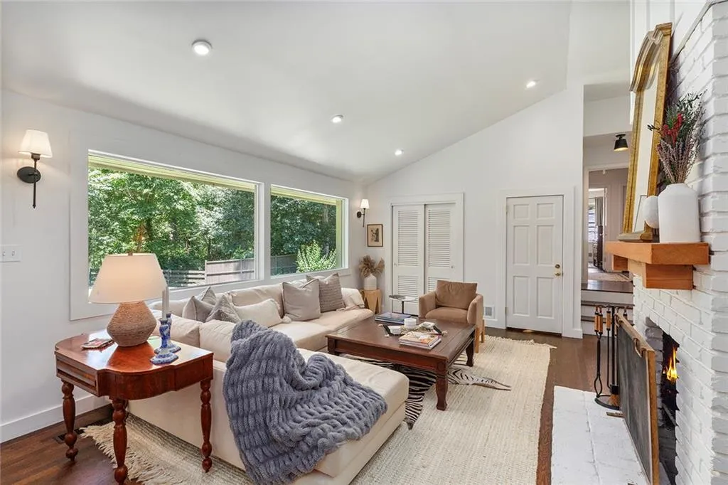 Living room with wood finished floors, lofted ceiling, recessed lighting, and a fireplace
