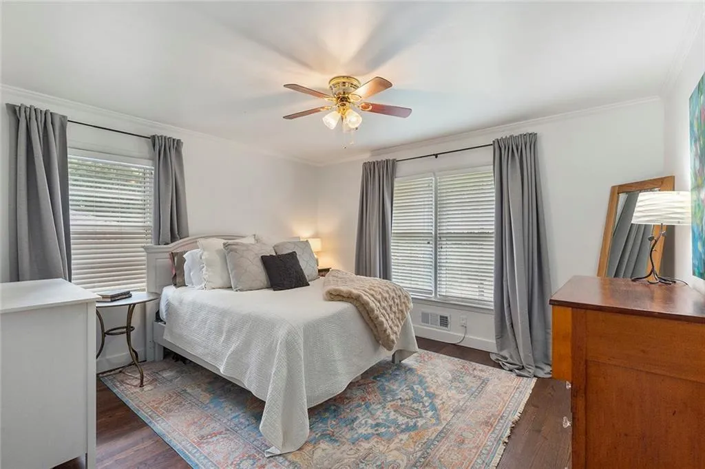 Bedroom with dark wood-style flooring, crown molding, and ceiling fan