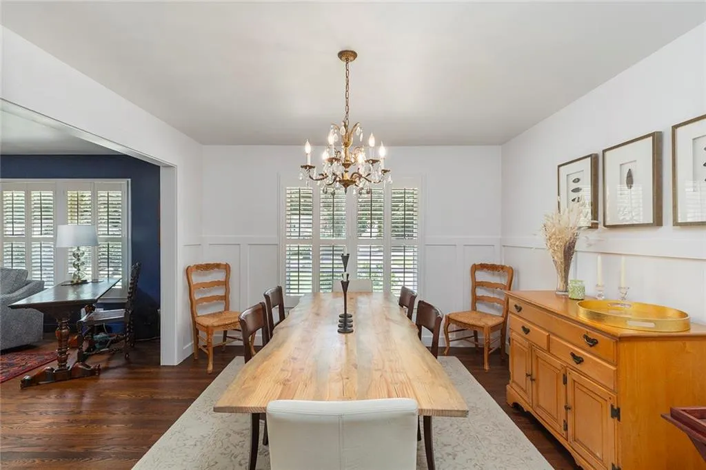 Dining area featuring a decorative wall, a chandelier, dark wood finished floors, healthy amount of natural light, and a wainscoted wall