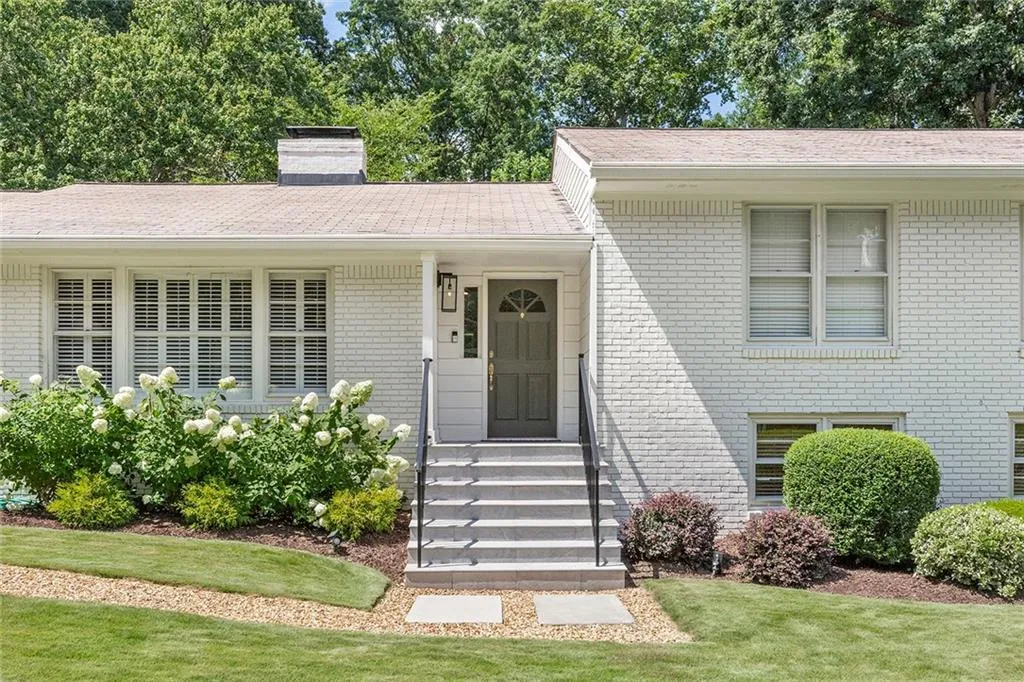 Tri-level home featuring brick siding, a chimney, and a front yard