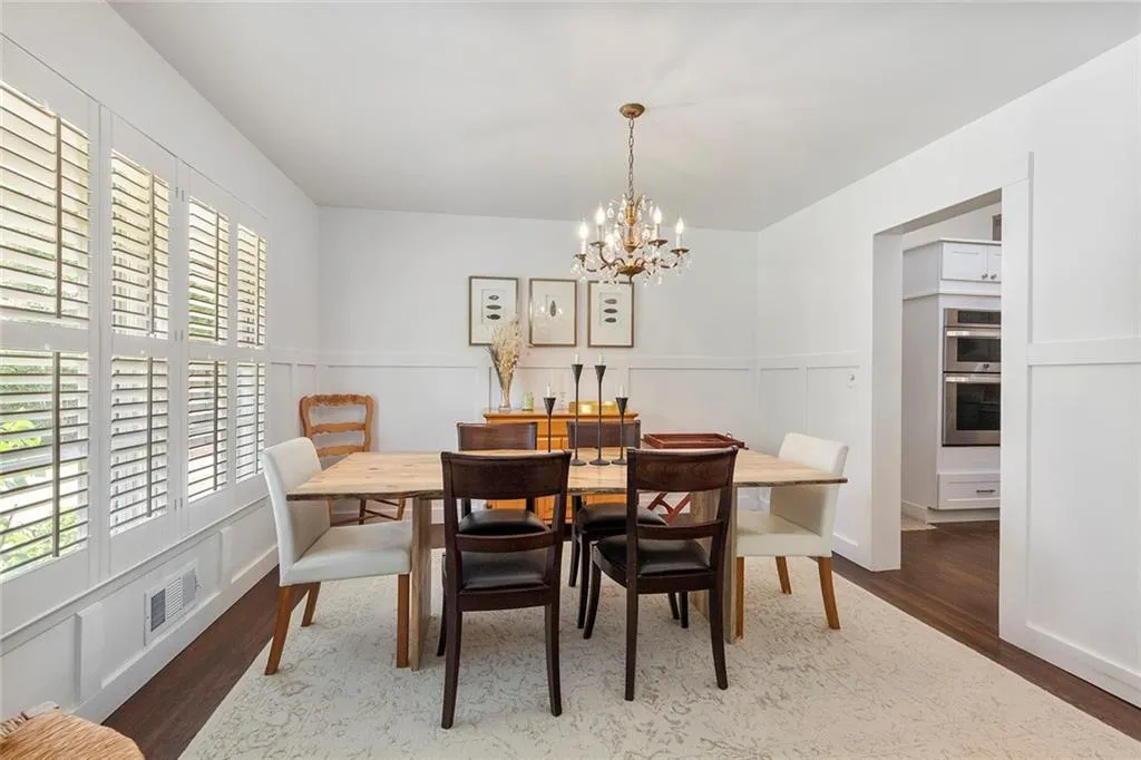 Dining room with wood finished floors, a chandelier, and a wainscoted wall