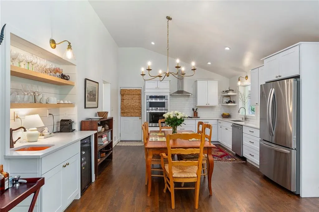Kitchen featuring open shelves, appliances with stainless steel finishes, vaulted ceiling, tasteful backsplash, and light countertops