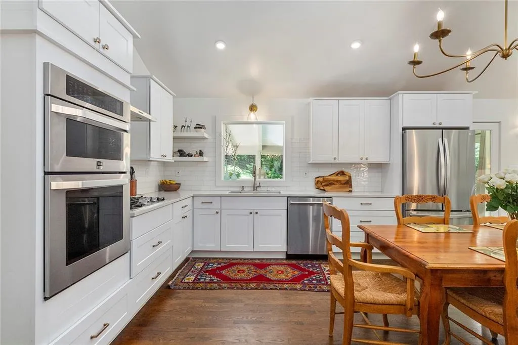 Kitchen featuring appliances with stainless steel finishes, open shelves, dark wood-type flooring, light countertops, and decorative backsplash