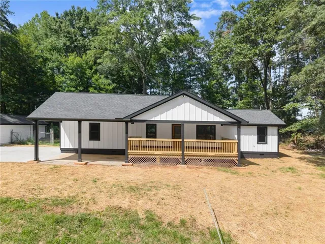 Modern farmhouse exterior with white vertical siding, black trim, and a covered front porch