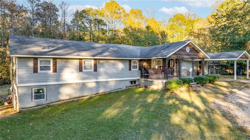 Ranch-style house featuring covered porch and a front lawn