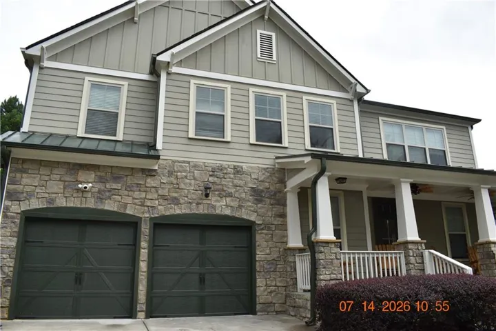 Two-story exterior with stone facade, siding, and a covered front porch featuring white columns