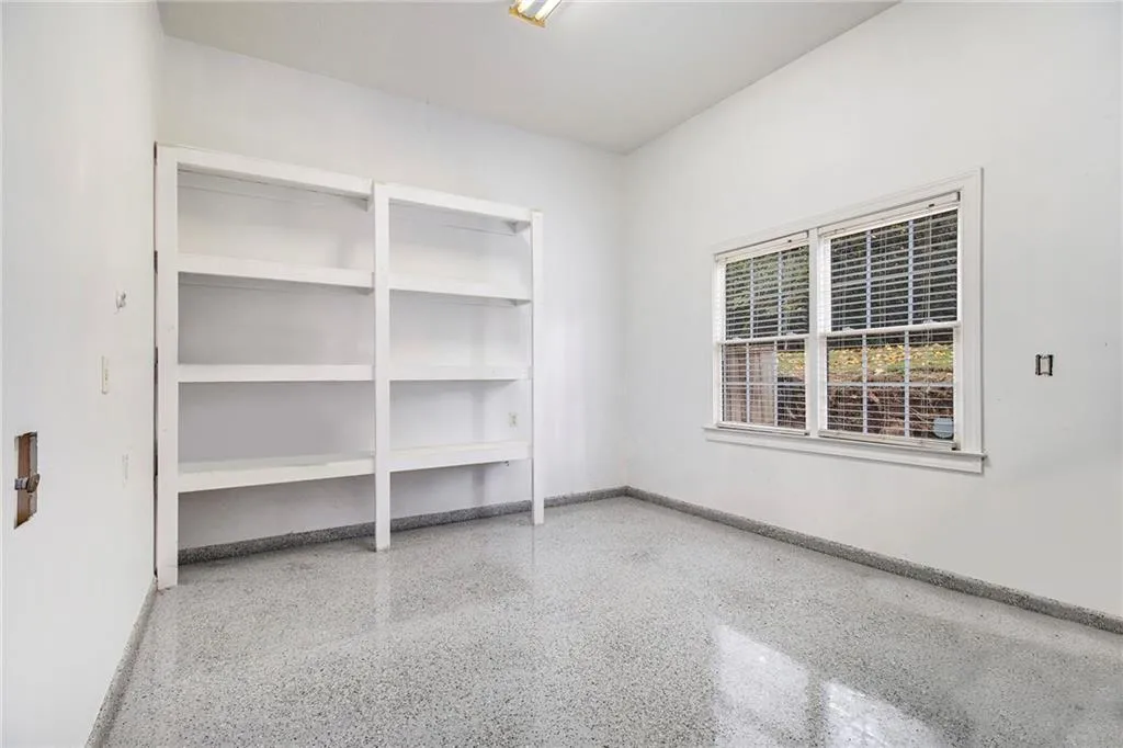 Unfurnished room featuring dark speckled floor and baseboards