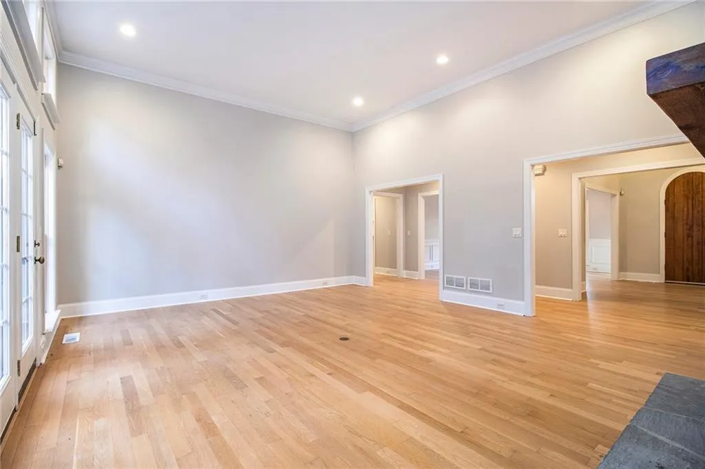 Unfurnished living room with arched walkways, light wood-style flooring, ornamental molding, recessed lighting, and a towering ceiling